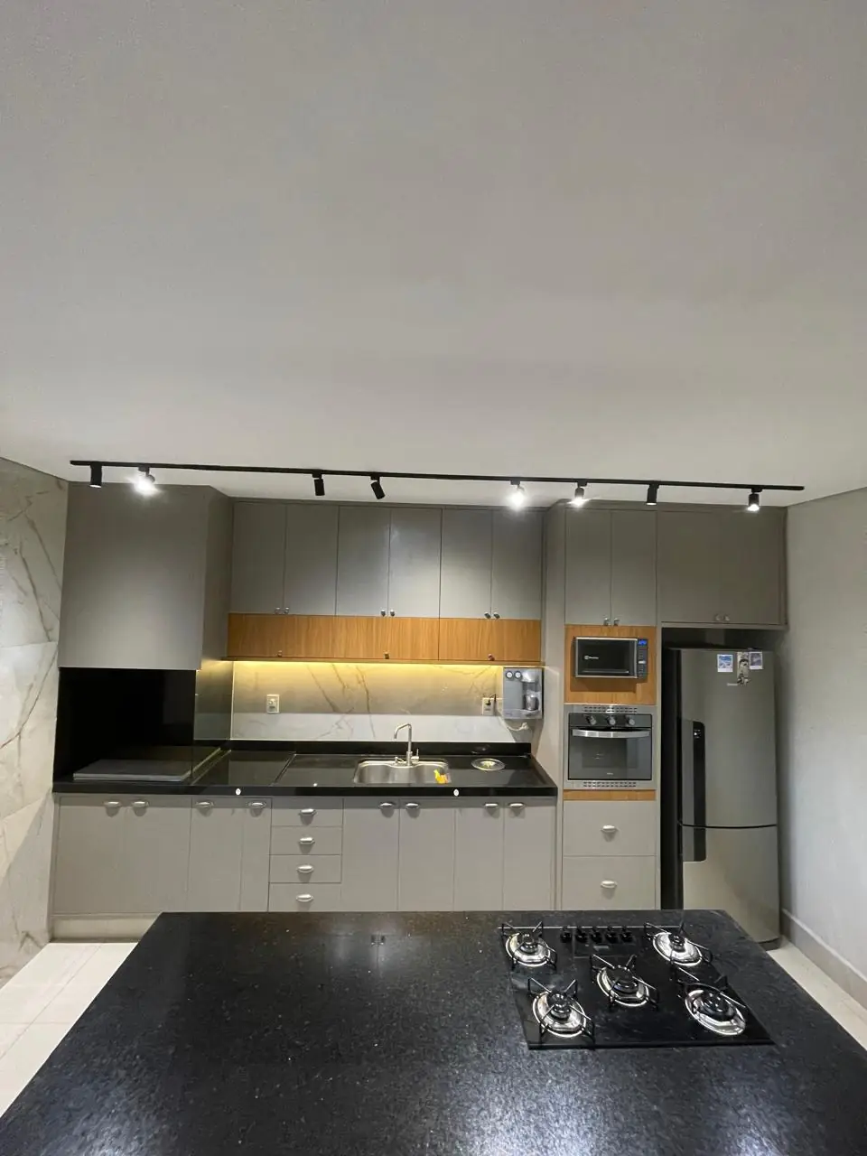 Cozinha planejada com ilha e iluminação em trilho